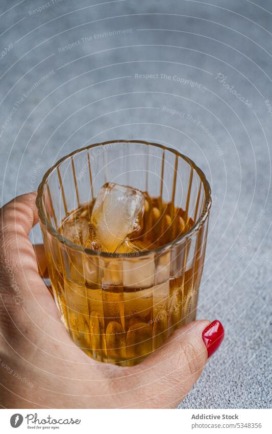 Glas mit Getränk und Eis Alkohol Cognac Cola kalt Kristalle Würfel Abendessen trinken Hand Halt rot ruhen stark Tisch Vodka Frau Ernte anonym unkenntlich