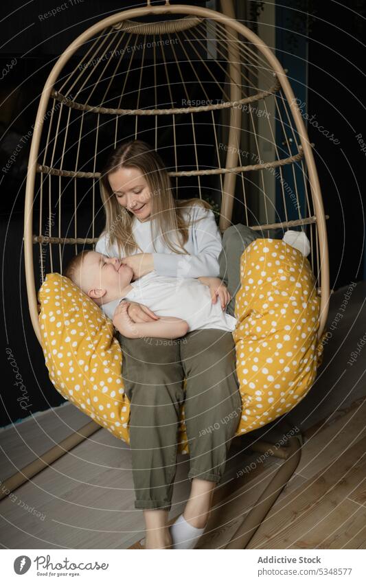 Frau mit Junge entspannt auf Hängesessel in Haus Mutter Sohn Weide Stuhl hängen Zusammensein Lächeln Freizeit Komfort ruhen Glück sich[Akk] entspannen