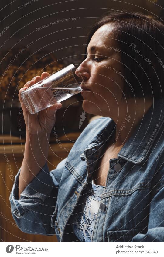 Ruhige reife Frau trinkt Wasser aus einem Glas trinken Küche friedlich Augen geschlossen Windstille Getränk Durst heimwärts Erfrischung ruhig Jacke Kurze Haare