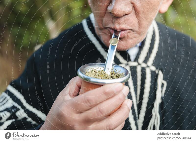 Abgeschnittener älterer Mann trinkt heißes Getränk im Park Yerba Partnerin Stroh gestrickt trinken mapuche einheimisch temuco Chile chilenisch traditionell