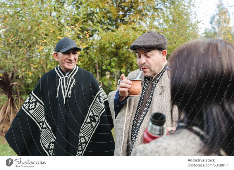 Lächelnde ältere Freunde mit Getränken im Park zusammen Männer Frau Yerba Partnerin mapuche Zeit verbringen Thermoskanne Zusammensein Gras trinken Freundschaft