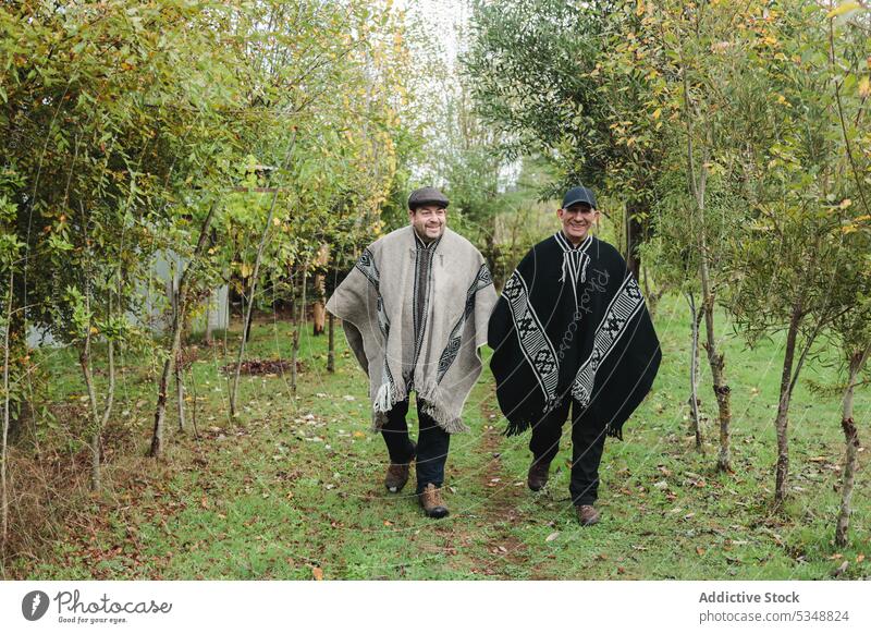 Fröhliche ältere Männer gehen gemeinsam im Garten spazieren diskutieren Spaziergang mapuche schlendern Gespräch reden Kommunizieren positiv Ernte Zusammensein