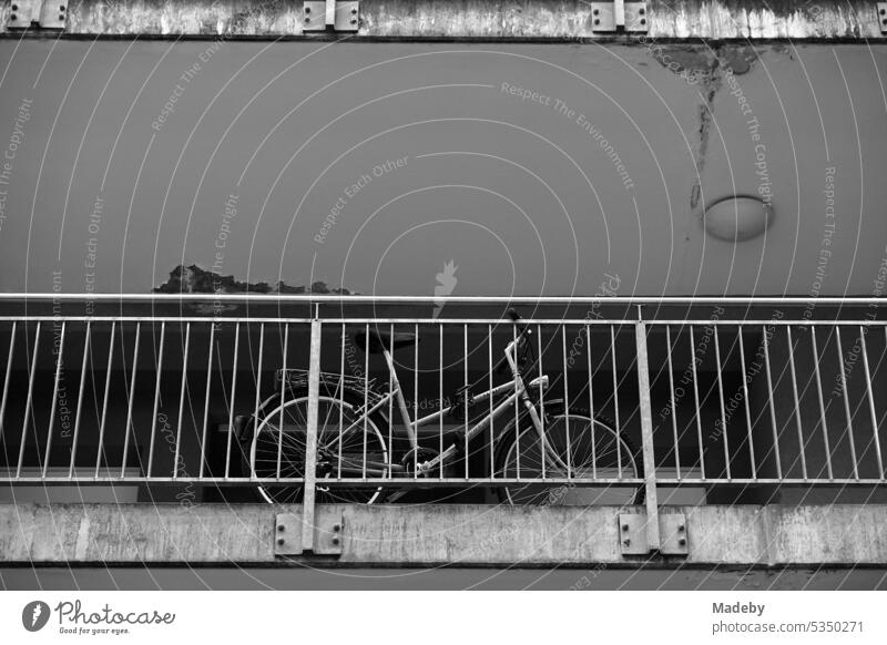 Fahrrad auf dem Balkon eines heruntergekommenen grauen Wohnhaus und Mietshaus mit Geländer im Masthildenviertel in Offenbach am Main in Hessen in neorealistischem Schwarzweiß