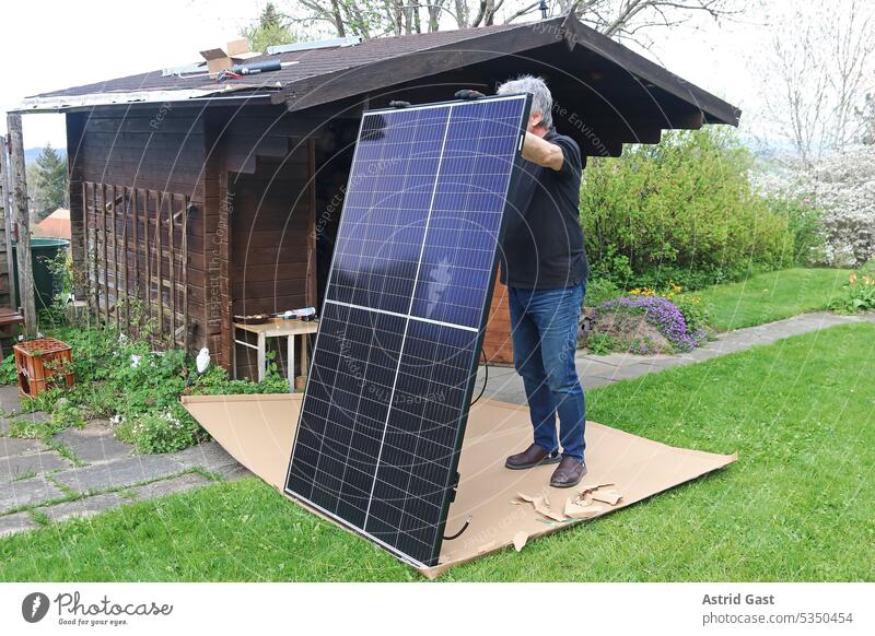 Ein Mann möchte eine kleine Solaranlage auf einem Gartenhaus montieren balkonkraftwerk gartenhaus dach solar stromerzeugung stromerzeugen solarmodule montage
