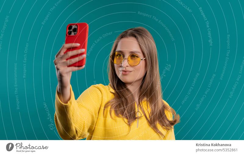 Trendy junge Frau macht Selfie auf Smartphone auf blauem Hintergrund. Erwachsener App attraktiv schön Schönheit lässig Kaukasier Zelle heiter