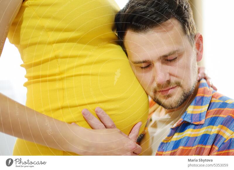 Junge Familie erwartet ein Baby. Gut aussehender Mann berührt den Bauch der schwangeren Frau und spürt die Bewegungen des Kindes. Zukunft Papa Vater Paar