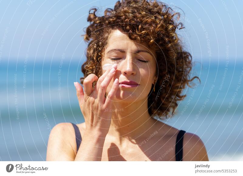Sinnliche Frau trägt Sonnenschutzmittel auf das Gesicht auf Strand bewerben Sonnencreme Sommerzeit behüten Hautpflege MEER Urlaub sinnlich jung krause Haare