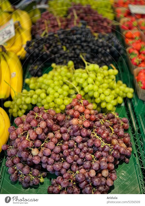 Wochenmarkt | verschiedene Weintrauben zwischen Bananen und Erdbeeren Trauben grün rot blau kernlos Erdbeerschalen Markt Verkauf Marktstand Obst Frucht