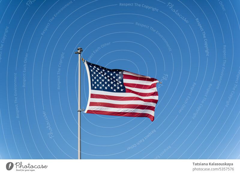 Die Flagge der Vereinigten Staaten von Amerika flattert im Wind gegen einen klaren blauen Himmel. Wehende USA-Flagge Fahne Stars and Stripes usa-fahne Mast