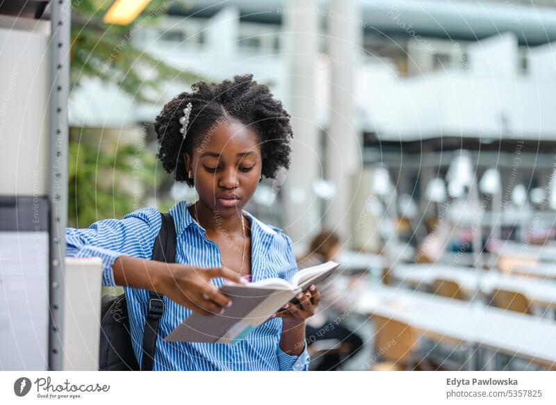 Schwarze Studentin liest ein Buch in einer Bibliothek echte Menschen Teenager Campus positiv Prüfung Wissen selbstbewusst schulisch Erwachsener Lifestyle