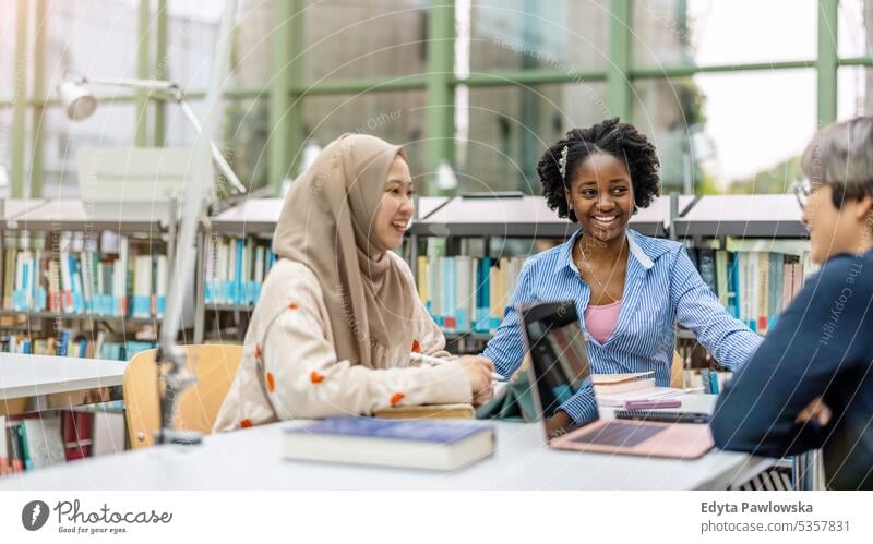 Gruppe multiethnischer Studenten bei einer Diskussion in einer Bibliothek echte Menschen Teenager Campus positiv Prüfung Wissen selbstbewusst schulisch