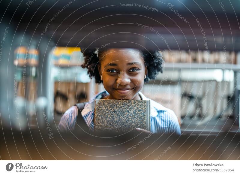 Porträt einer schwarzen Studentin, die in einer Bibliothek steht echte Menschen Teenager Campus positiv Prüfung Wissen selbstbewusst schulisch Erwachsener