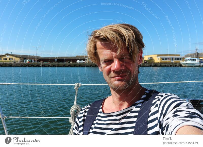ein Mann im gestreiften Hemd auf einen Schiff im Hafen Dänemark Wasser Boot Außenaufnahme Himmel maritim Farbfoto blau Tag Meer Schifffahrt blond Sommer warm