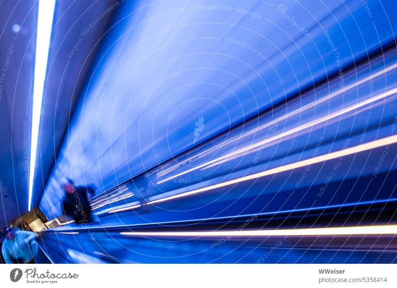 Dynamische Linien aus Licht rasen in einem blauen Tunnel auf einen Fluchtpunkt zu Rolltreppe Schacht Aufstieg verschwommen dynamisch rasant Bewegung schnell
