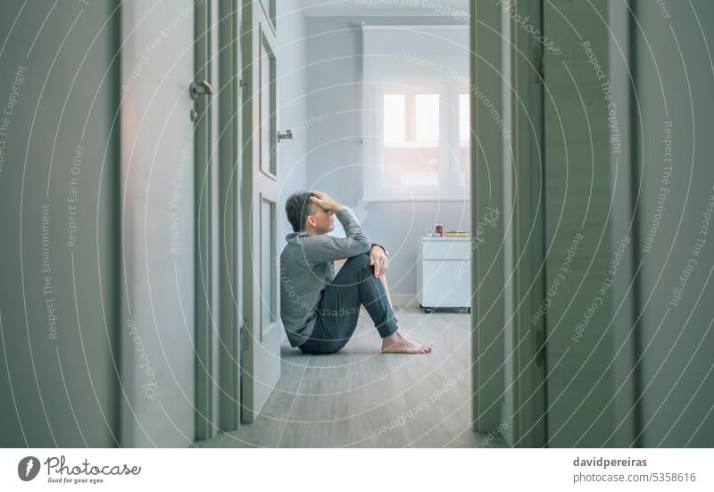 Mann mit psychischer Störung und Selbstmordgedanken sitzt auf dem Zimmerboden mental Erkrankung Gedanken selbstmörderisch Gesundheit verzweifelt Problematik
