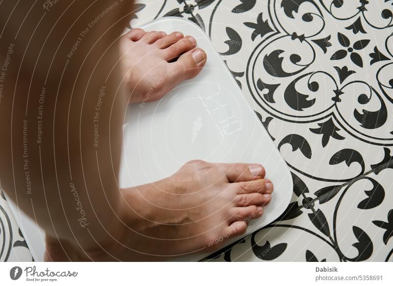 Frau überprüft ihr Gewicht auf einer Waage im Badezimmer Skala Schuppen Kontrolle Fuß digital Körper messen Diät Gesundheit Hintergrund Gleichgewicht Fett