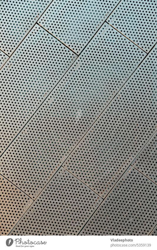 Metallperforierte Wandfliesen eines zeitgenössischen Gebäudes. Fassade Wand. Konstruktion, archetecture Textur Muster diagonal durchlöchert schwarz abstrakt
