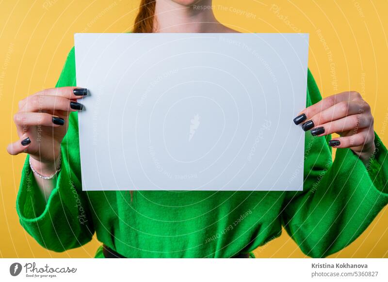 Junge Frau hält ein horizontales weißes A4-Papierplakat. Platz zum Kopieren. Anzeige Inserat Hintergrund Plakatwand blanko Holzplatte Heft Business
