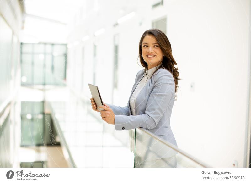 Junge Frau bei der Arbeit an einem digitalen Tablet im Büroflur Apparatur Kaukasier Glück Mitarbeiter professionell Exekutive Tablette Geschäftsfrau Flur