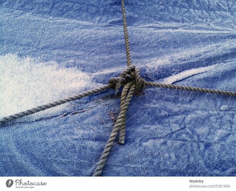 Schiffstau über einer vereisten blauen Plane aus Kunststoff im Winter auf einem Bootsanhänger in Oerlinghausen bei Bielefeld am Hermannsweg im Teutoburger Wald in Ostwestfalen-Lippe