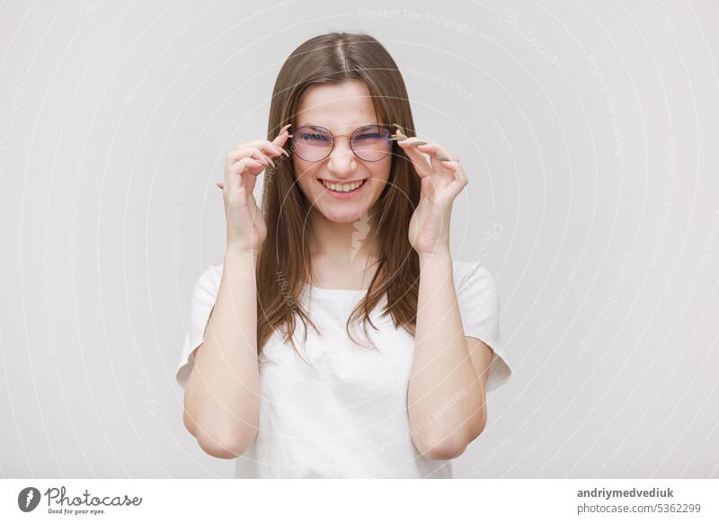 hübsches teenager-mädchen mit brille hat spaß auf einem weißen hintergrund. weiblich in weißem t-shirt mit langen haaren im studio Teenager Lifestyle lustig