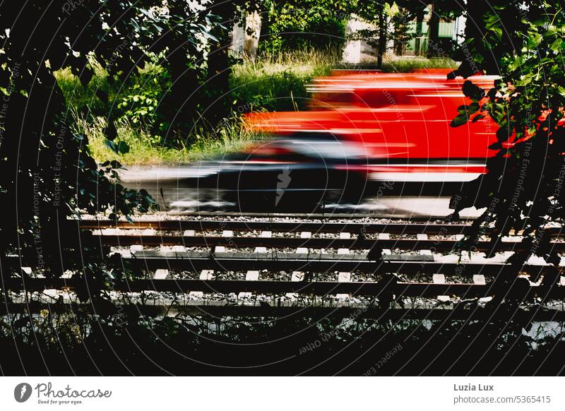 Gleise und Straße, ein roter Feuerwehrwagen fährt viel zu schnell... Bahn Stadtbahn Verkehr Schienenverkehr fahren Gleisbett Sommer sommerlich