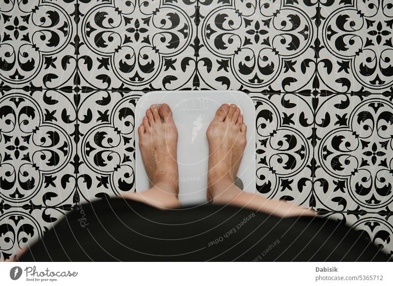 Frau überprüft ihr Gewicht auf einer Waage im Badezimmer Skala Schuppen Kontrolle Fuß digital Körper messen Diät Gesundheit Hintergrund Gleichgewicht Fett