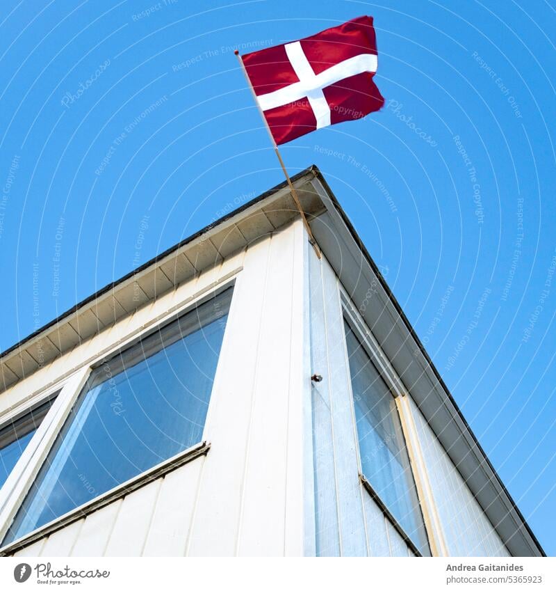 Blick nach oben an einem Badehaus am Strand von Løkken, oben mittig im Bild eine wehende dänische Fahne, Teilaufnahme, quadratisch, 1:1 Badehäuschen Dänemark