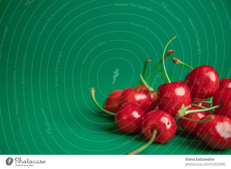 Rote Kirschen auf einem grünen Hintergrund süßkirschen Sommer Frucht frisch lecker Textfreiraum oben Textfreiraum links Werbung Werbebranche Plakat Flyer Motiv
