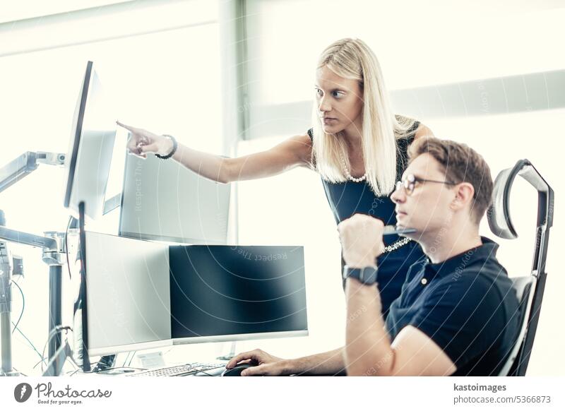 Das Team eines Börsenmaklers, das online handelt, beobachtet Charts und Datenanalysen auf mehreren Computerbildschirmen in einem modernen Büro mit Firmenarbeitsplatz.