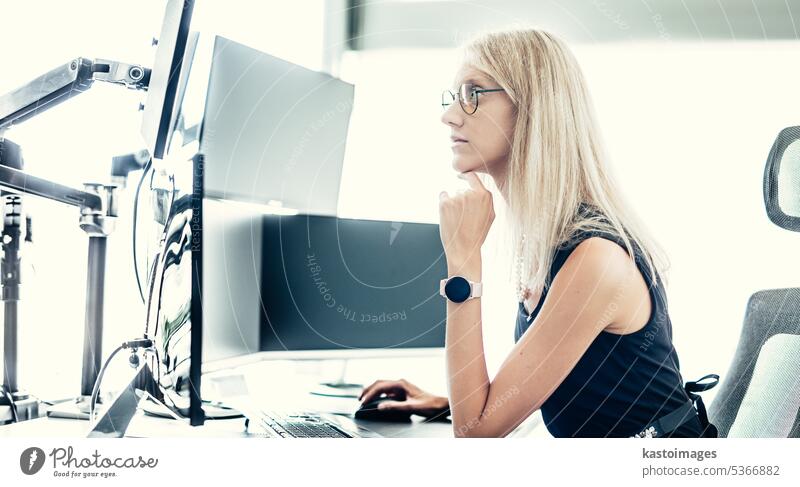 Weibliche Managerin von Finanzanlagen, die online handelt und Charts und Datenanalysen auf mehreren Computerbildschirmen beobachtet. Moderne Corporate Business Frau Konzept.