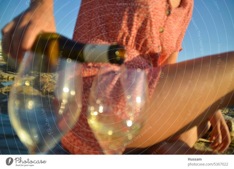 Foto der Hand einer Dame, die am Strand Wein einschenkt Weinglas feiern Lifestyle MEER Sektglas Prosecco trinken Sommer Glas Getränk zu feiern goldene Stunde