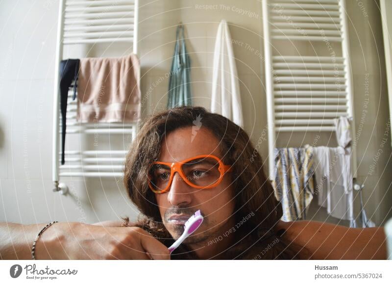Foto einer Person im Badezimmer, die sich die Zähne putzt und mit einer flippigen Brille vom Tag träumt Mann schöne Menschen Morgenroutine gut aussehend Hygiene