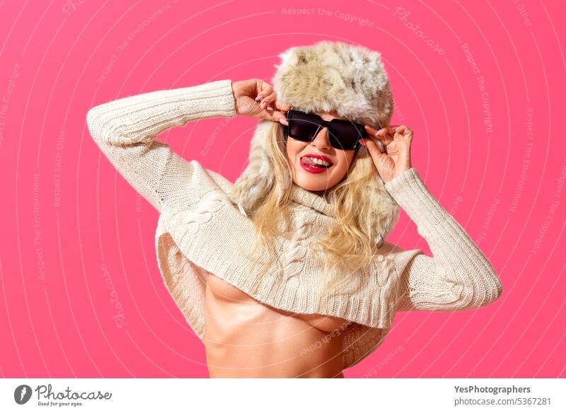 Lustiges Sommerkonzept, eine Frau mit Winterkleidung und Sonnenbrille Einstellung Hintergrund schön blond hell Klima Kleidung Farbe Konzept Textfreiraum