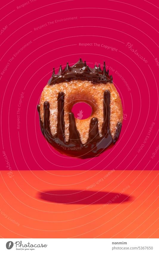 Schwimmende schokoladenüberzogene Ringkrapfen Königin Konzept fliegend Schokolade belegt Doughnut pulsierend rosa orange Krapfen Krone Tropfen geschmolzen