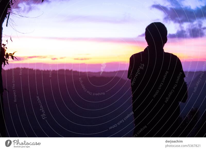 Ein Mann mit dem Rücken gewandt  schaut dem  Himmels Spektakel-  Sonnenuntergang mit allen Farben zu die Natur zu bieten hat,  in Binna Burra.