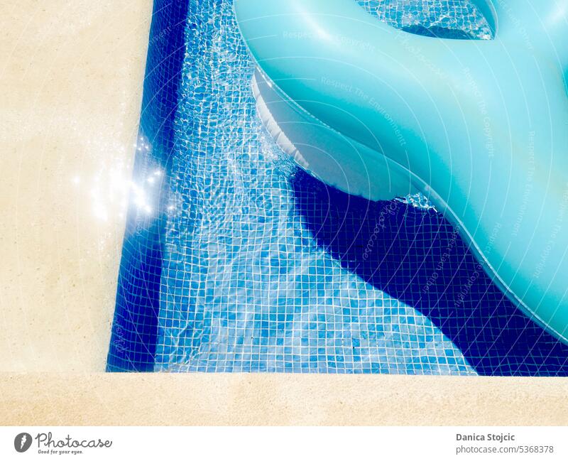 Schwimmende blaue Luftmatratze im blauen Mosaik-Swimmingpool mit Lichtreflexen auf dem Wasser kinderplanschbecken Urlaub Ferien relax Erholung Erfrischung