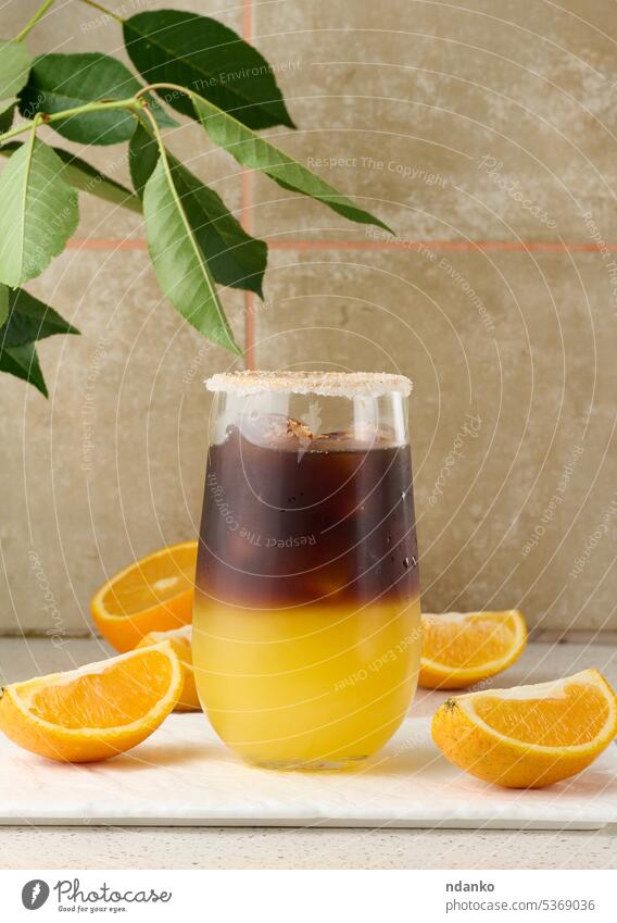 Kalter Kaffee mit Orangensaft in einem durchsichtigen Glas und Orangenspalten orange braun süß cool Eis Espresso kalt trinken frisch Saft Getränk Cocktail