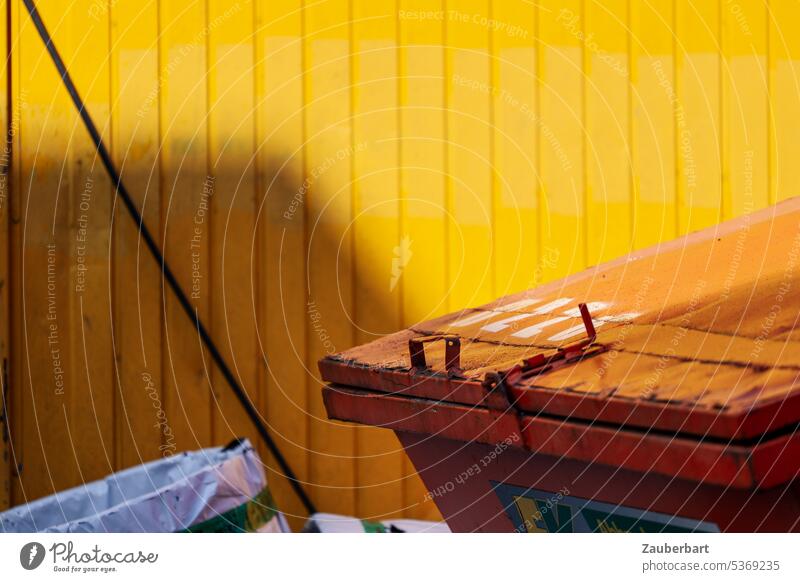 Container in orange vor gelber Wand Fassade Industriegebiet clash Farbe farbig bunt sonnig Schatten Abfall Beseitung Müll