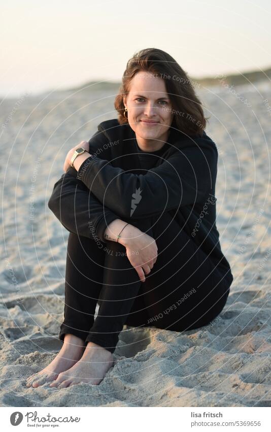 SAND - FRAU - ABENDDÄMMERUNG Frau 30-35 Jahre Erwachsene Farbfoto Sand Strand gemütlich schwarze Kleidung kurzhaarig brünett Lächeln Zufriedenheit natürlich