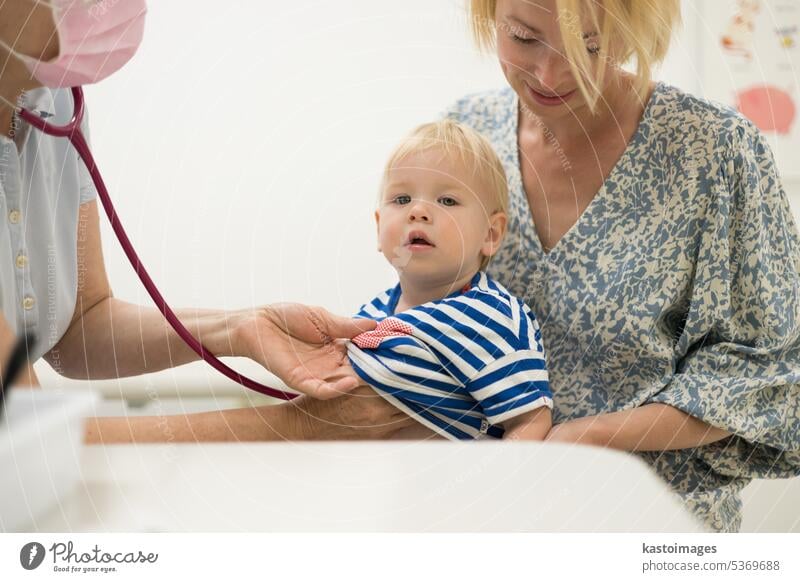 Kleinkind Junge Kind wird von seinem Kinderarzt Arzt während einer Standard-medizinischen Check-up in Anwesenheit und Komfort seiner Mutter untersucht. Nationales Konzept für öffentliche Gesundheit und Kinderbetreuung.