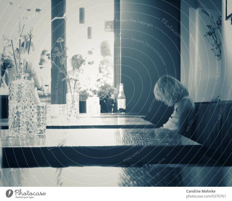 Ein Kind sitzt alleine im Café und schaut auf sein Handy Kinder Smartphone Lifestyle Telefon Mobile Mitteilung benutzend Internet digital Gerät Bildschirm