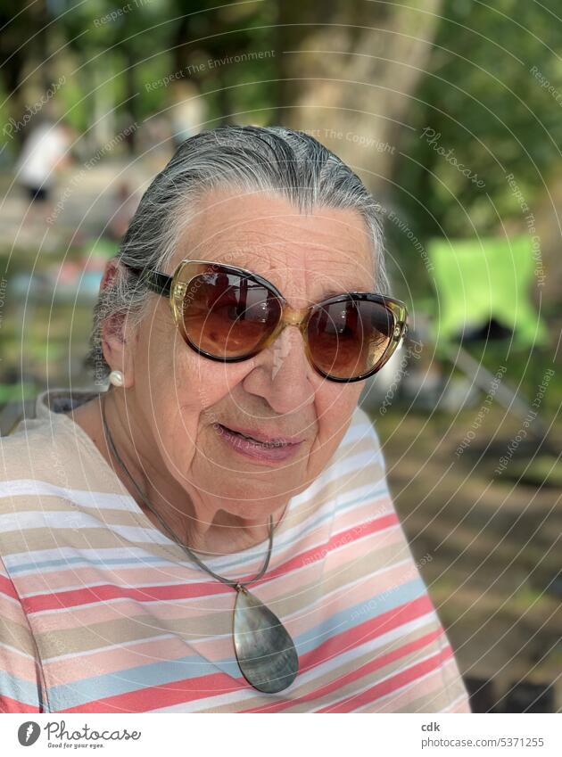 Die Sommerfrische am See genießen: zufriedene Seniorin mit Sonnenbrille beobachtet das Geschehen. Mensch Dame Frau Porträt Erwachsene Rentnerin Großmutter