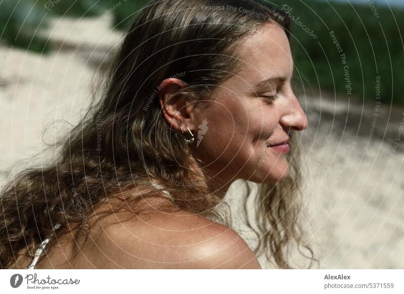 seitliches Portrait einer jungen, schönen, brünetten, lächelnden Frau mit Grübchen im Bikini am Strand warm sommerlich schönes wetter Sommer Nähe Tag