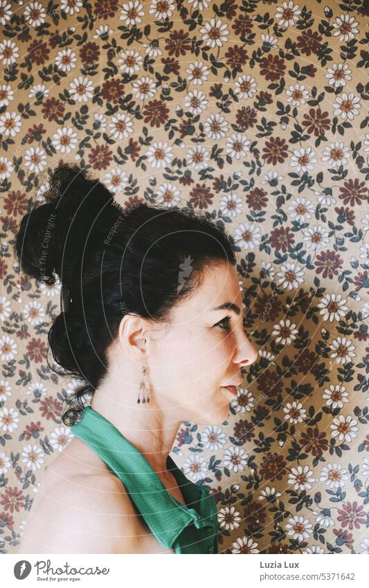 Schöne Frau mit aufgestecktem, schwarzem Haar im Profil vor einer altmodischen Tapete... schön schwarzhaarig Locken Tapetenmuster Tapetenmuster-Hintergrund