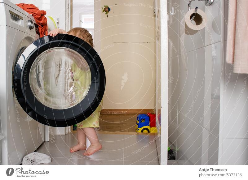 Kleinkind schaut in geöffnete Waschmaschine montessori Kind Wäsche waschen Waschtag Haushalt Alltagsfotografie dokumentarisch