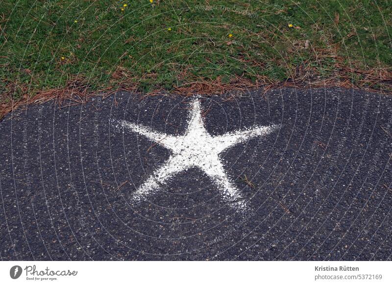 weißer stern auf grauem asphalt an grünem rasen fünfzackig zeichen symbol markierung kennzeichnung streetart straße boden gehweg gras