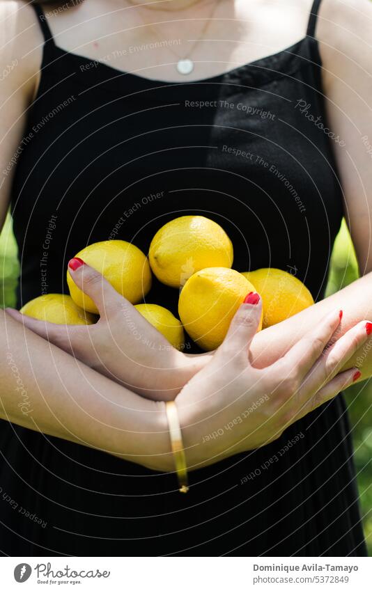 Zitronen in den Händen Frauenkörper die Arme verschränkt Armband rote Nägel Lifestyle Zitrusfrüchte Frucht Limonade zitronengelb schwarzes Kleid Erfrischung