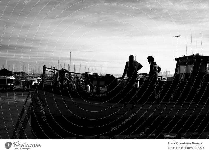 Zwei Männer auf einem Holzboot, das im Hafen von Punta del Este, Uruguay, aus dem Wasser steigt. menschlich schwarz auf weiß Schiff Boot hoher Kontrast
