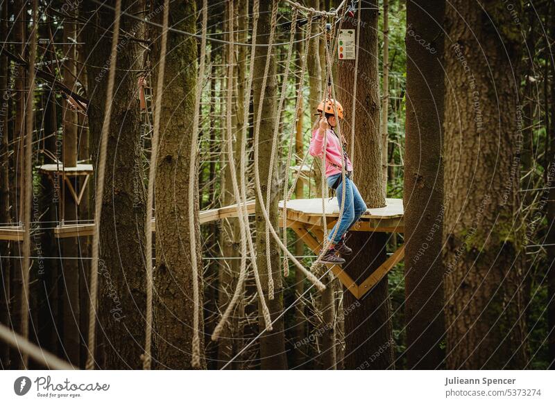 Kind auf einem Kletterseil im Freien unter Bäumen Baumkrone Baumwipfelpfad Kabelbaum Mädchen Aufstieg Seil Seile Hochseil extrem Aktivität Abenteuer Natur aktiv